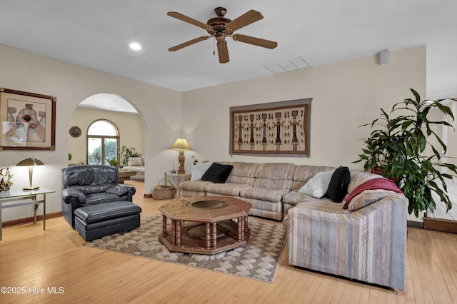 living room with arched walkways, visible vents, a ceiling fan, and wood-type flooring