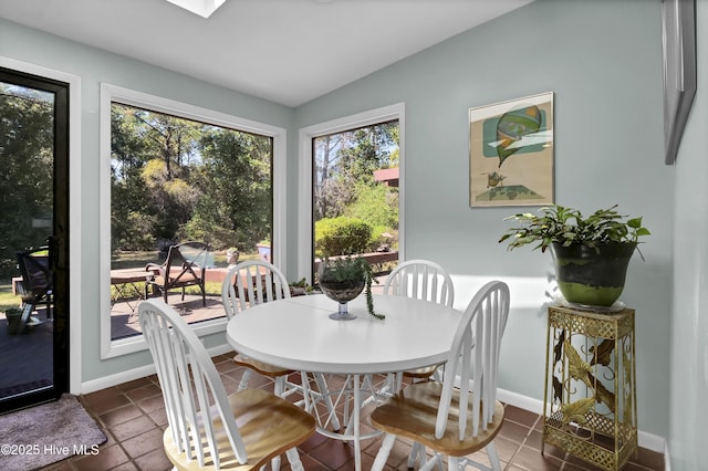dining room featuring baseboards, lofted ceiling, and dark tile patterned floors