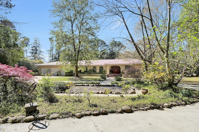 view of front of property featuring metal roof, stucco siding, an attached garage, and concrete driveway