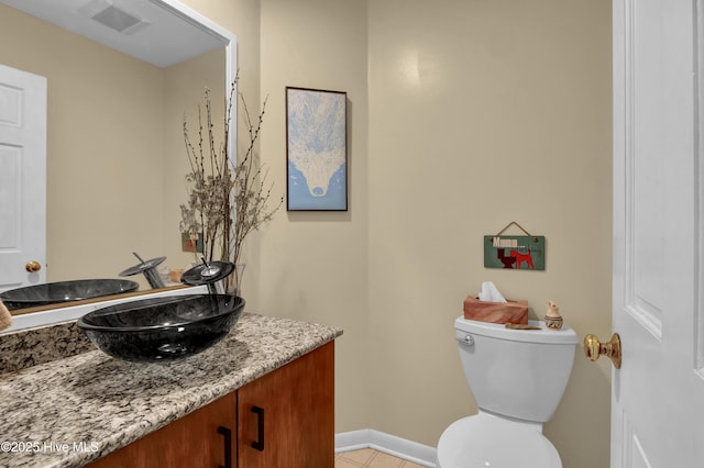 bathroom with toilet, vanity, baseboards, and visible vents