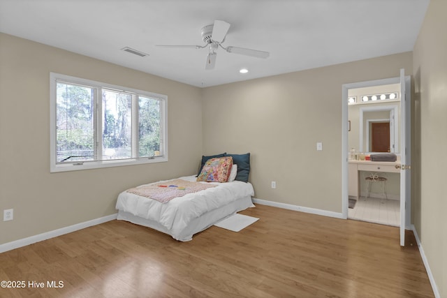 bedroom with ensuite bathroom, baseboards, light wood-style floors, and visible vents