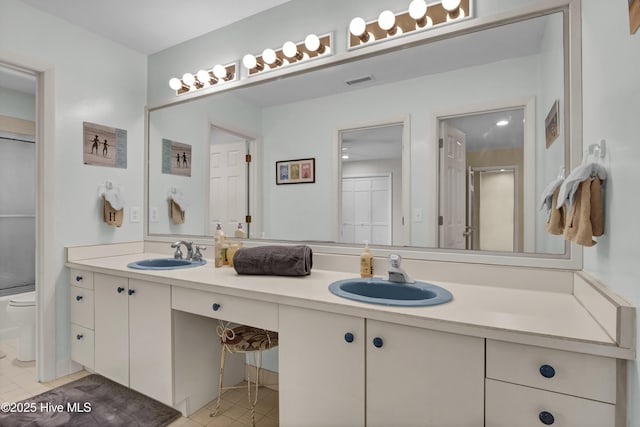bathroom with visible vents, a sink, toilet, and double vanity