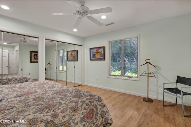 bedroom featuring two closets, recessed lighting, baseboards, visible vents, and wood finished floors