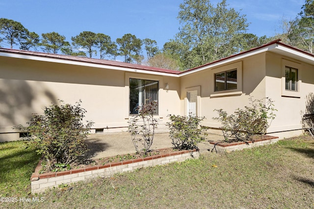 view of side of home featuring stucco siding and a yard