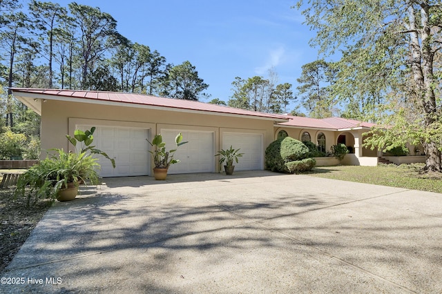 view of front of home featuring stucco siding, metal roof, a garage, and concrete driveway