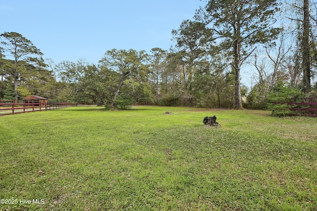view of yard with fence and a rural view