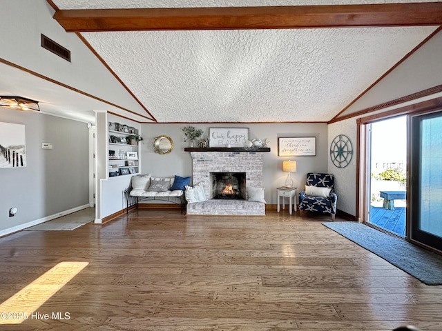 living room featuring a textured ceiling, wood finished floors, visible vents, and a brick fireplace