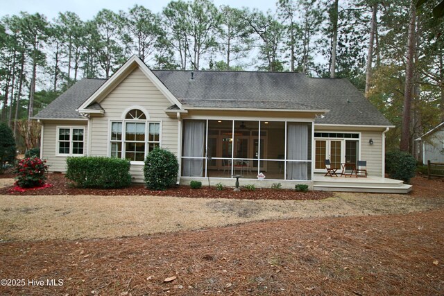 rear view of house with a deck, a shingled roof, and a sunroom