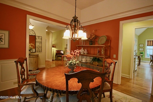 dining space with a chandelier, baseboards, wood finished floors, and ornamental molding