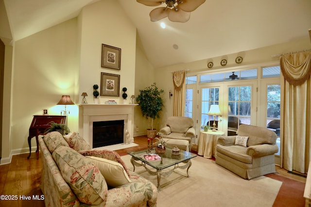 living room featuring a fireplace with flush hearth, high vaulted ceiling, a ceiling fan, baseboards, and wood finished floors