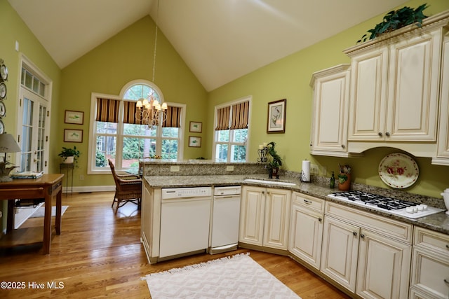 kitchen with a chandelier, light wood-style floors, white appliances, and a peninsula