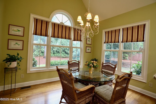 dining area with an inviting chandelier, a wealth of natural light, lofted ceiling, and baseboards