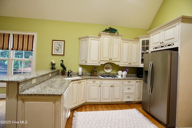 kitchen with a sink, white gas stovetop, light wood-type flooring, stainless steel refrigerator with ice dispenser, and a peninsula
