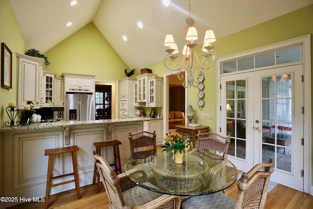 dining room featuring recessed lighting, an inviting chandelier, light wood-style floors, high vaulted ceiling, and french doors