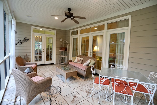 sunroom / solarium featuring wooden walls, a ceiling fan, and french doors