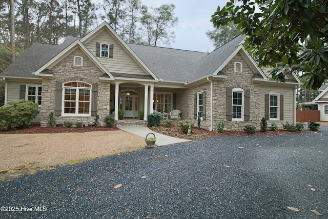 craftsman inspired home featuring stone siding and a shingled roof