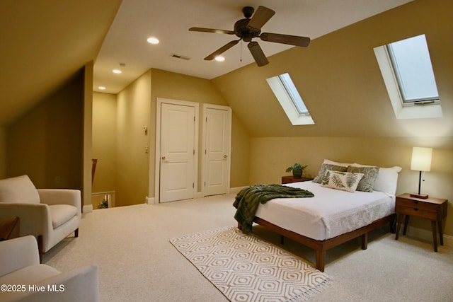 carpeted bedroom featuring vaulted ceiling with skylight, visible vents, ceiling fan, baseboards, and recessed lighting