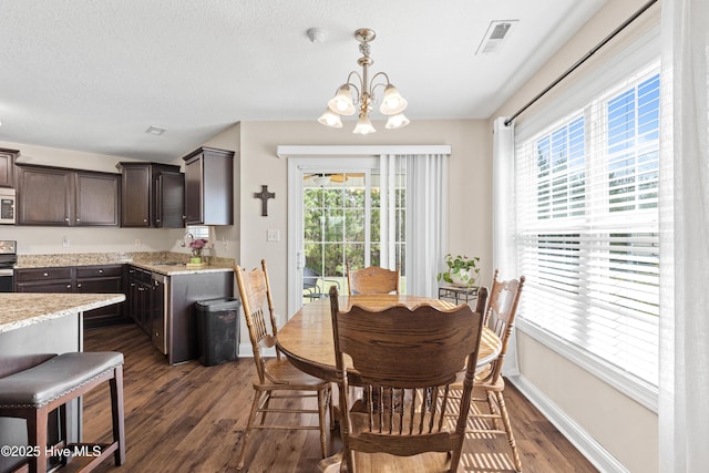 dining room with baseboards, dark wood finished floors, a textured ceiling, visible vents, and a notable chandelier