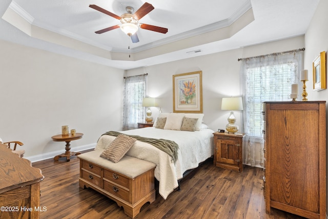 bedroom with a raised ceiling, dark wood-type flooring, and multiple windows