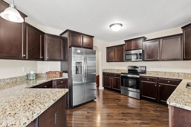kitchen featuring dark wood finished floors, arched walkways, appliances with stainless steel finishes, and dark brown cabinets