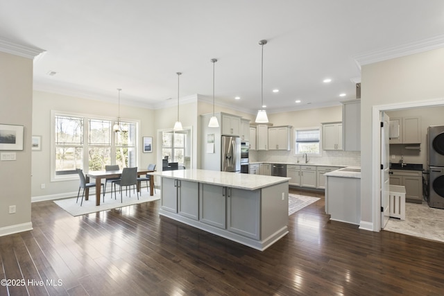 kitchen with gray cabinetry, a kitchen island, decorative backsplash, and stainless steel appliances