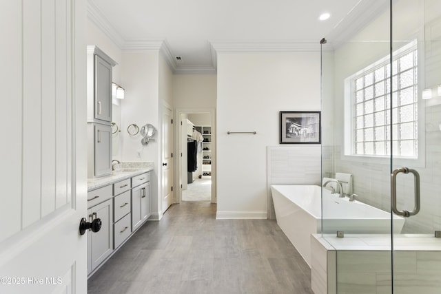 bathroom with ornamental molding, wood finished floors, a freestanding tub, and vanity