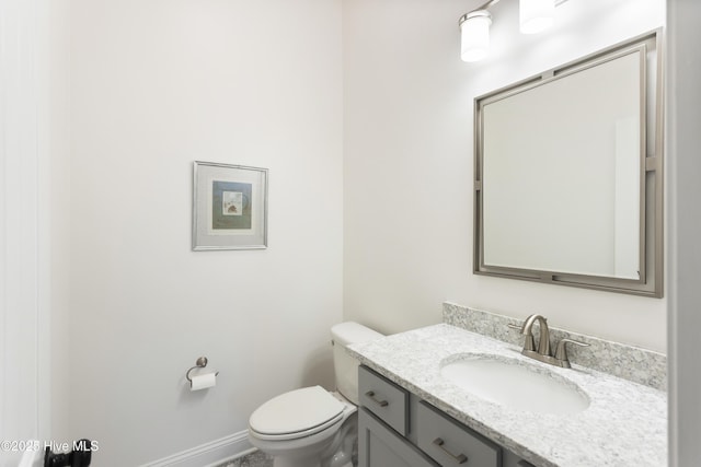 bathroom featuring toilet, vanity, and baseboards