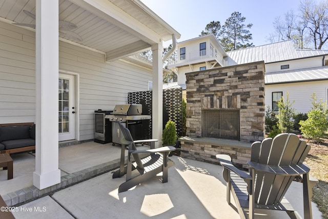 view of patio with an outdoor stone fireplace and grilling area