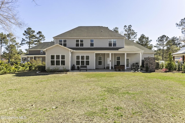 rear view of house featuring a lawn, roof with shingles, and a patio area
