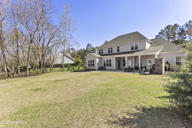 rear view of property with roof with shingles, a patio, and a yard