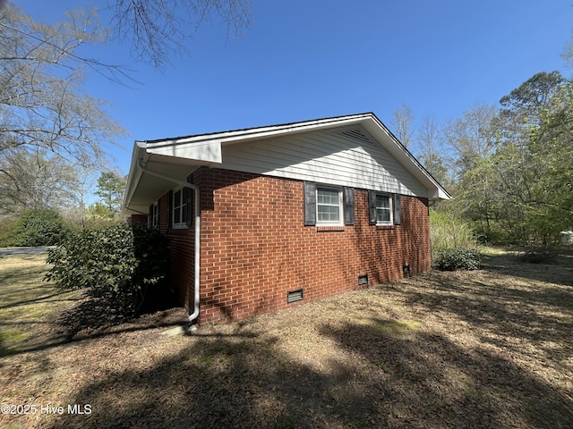 view of side of home featuring brick siding and crawl space