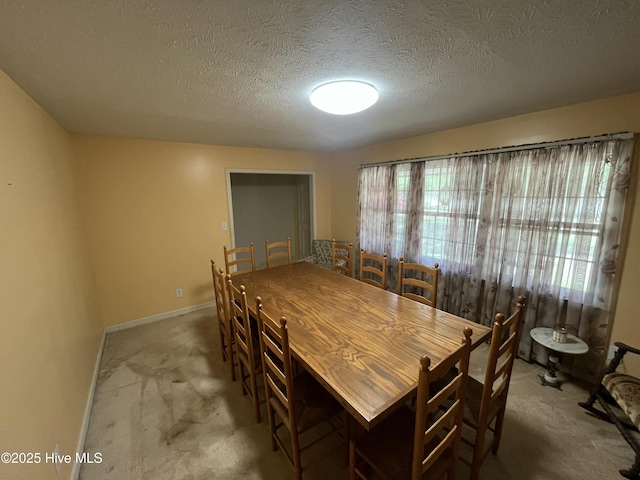 carpeted dining room featuring a textured ceiling and baseboards