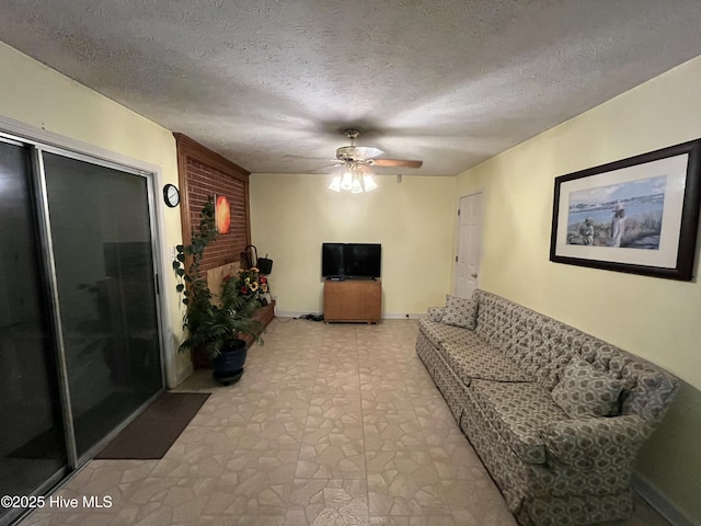 living area with a textured ceiling, baseboards, light floors, and ceiling fan
