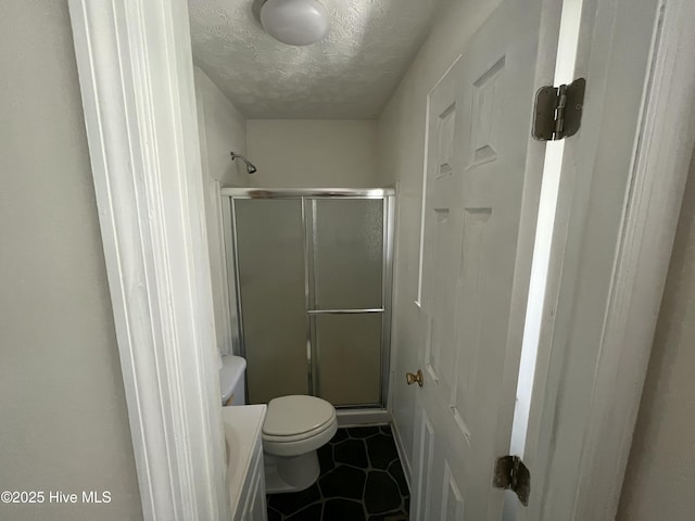 bathroom with tile patterned flooring, toilet, a stall shower, and a textured ceiling