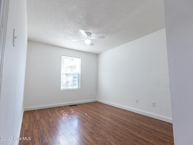 spare room with dark wood-style flooring, a textured ceiling, visible vents, baseboards, and ceiling fan