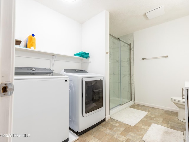 laundry area featuring stone finish floor, baseboards, washing machine and dryer, and laundry area