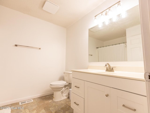 bathroom with visible vents, stone finish floor, baseboards, toilet, and vanity