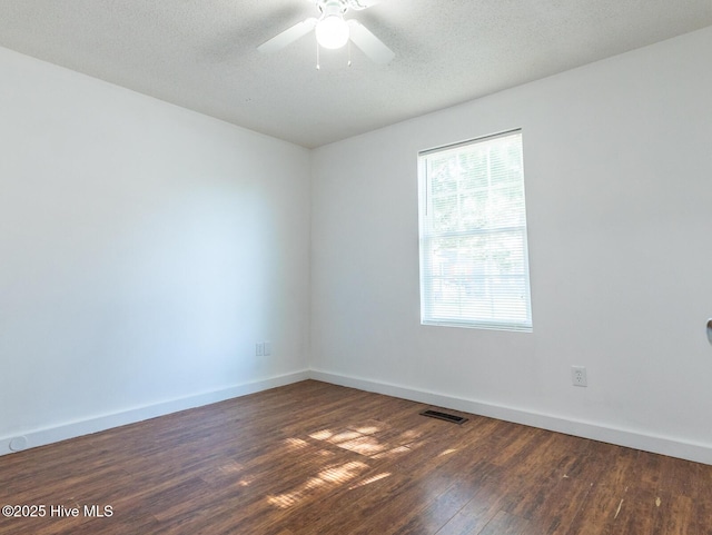 empty room with a textured ceiling, visible vents, baseboards, wood finished floors, and a ceiling fan