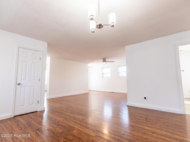 spare room with ceiling fan with notable chandelier, wood finished floors, baseboards, and a textured ceiling