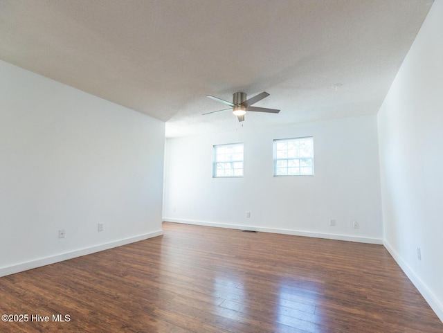 empty room featuring a ceiling fan, dark wood-style flooring, and baseboards
