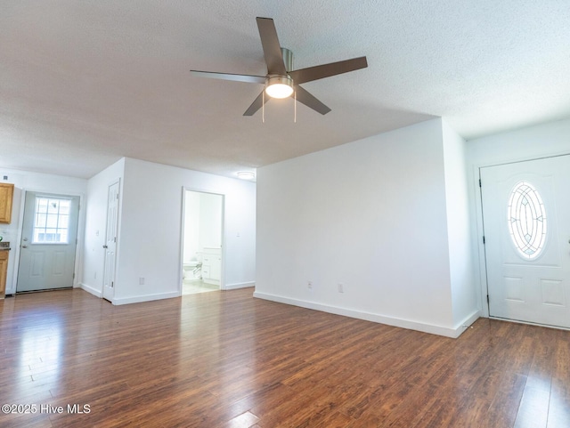 unfurnished living room featuring a textured ceiling, dark wood-style flooring, ceiling fan, and baseboards