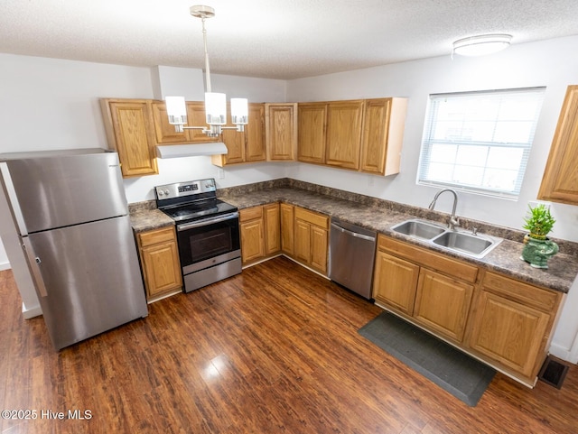 kitchen featuring stainless steel appliances, under cabinet range hood, dark wood finished floors, a sink, and visible vents