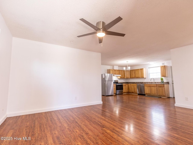unfurnished living room featuring baseboards, dark wood-style floors, and ceiling fan with notable chandelier