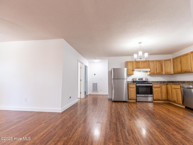kitchen featuring dark wood-style flooring, stainless steel appliances, under cabinet range hood, visible vents, and a notable chandelier