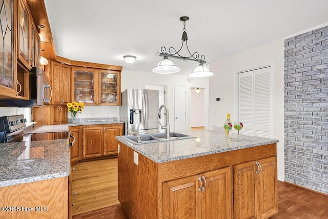 kitchen featuring a sink, appliances with stainless steel finishes, light wood finished floors, and brown cabinets