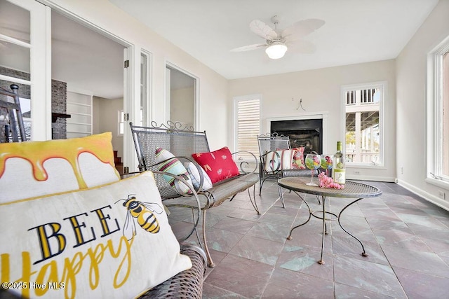 interior space with baseboards, a ceiling fan, and a fireplace