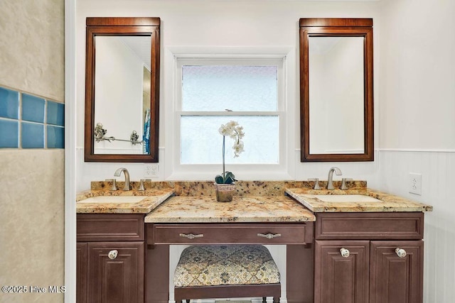full bathroom featuring vanity and a wainscoted wall