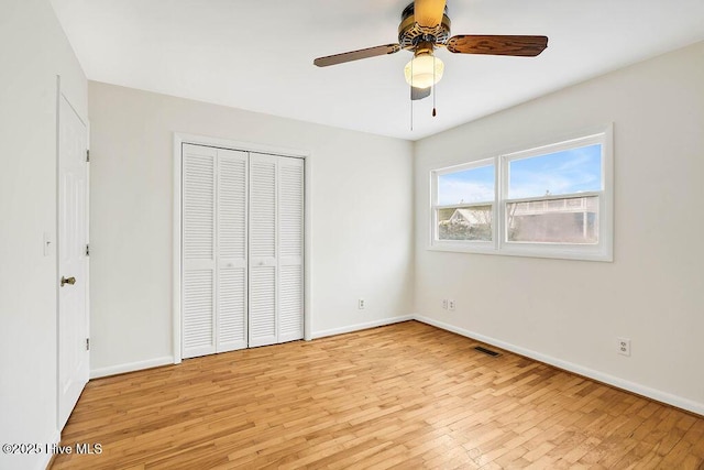 unfurnished bedroom featuring a closet, baseboards, visible vents, ceiling fan, and light wood finished floors