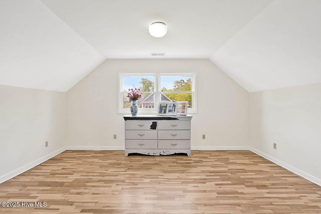 additional living space with light wood finished floors, lofted ceiling, and visible vents