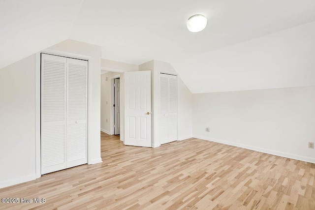 additional living space with light wood-style flooring, vaulted ceiling, and baseboards